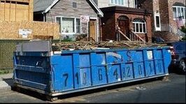 A large blue dumpster filled with construction waste